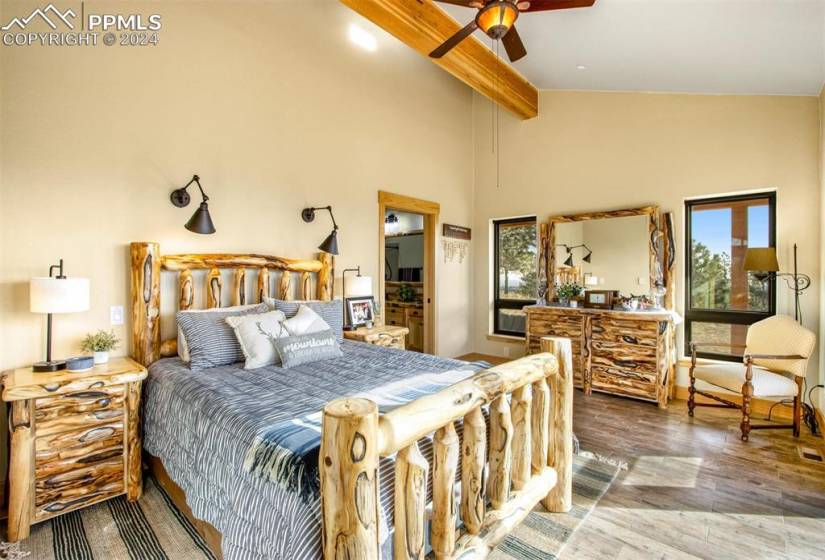 Bedroom featuring ceiling fan, multiple windows, hardwood / wood-style flooring, and beam ceiling