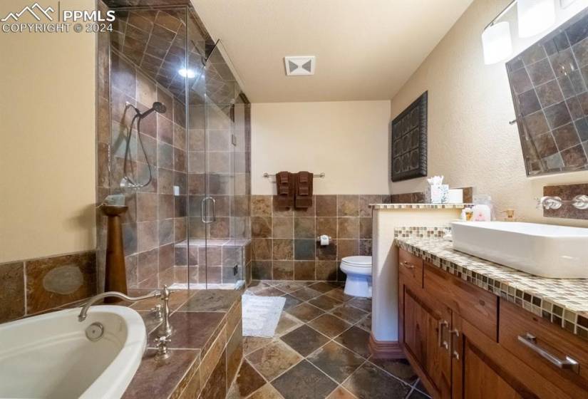 Full bathroom with tile flooring, plus walk in shower, tile walls, vanity, and toilet