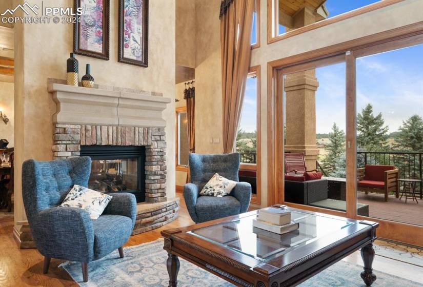 Living room featuring a stone fireplace, a towering ceiling, and hardwood / wood-style flooring