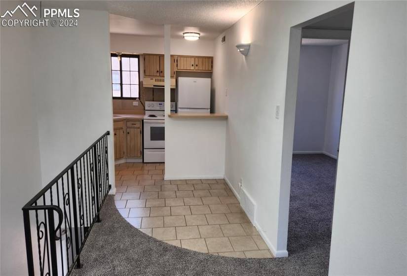 Kitchen featuring white appliances, a textured ceiling, backsplash, and light colored carpet