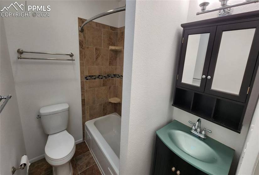 Full bathroom with tiled shower / bath, vanity, toilet, and tile flooring