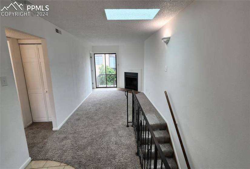 Hallway with carpet flooring, a textured ceiling, and a skylight