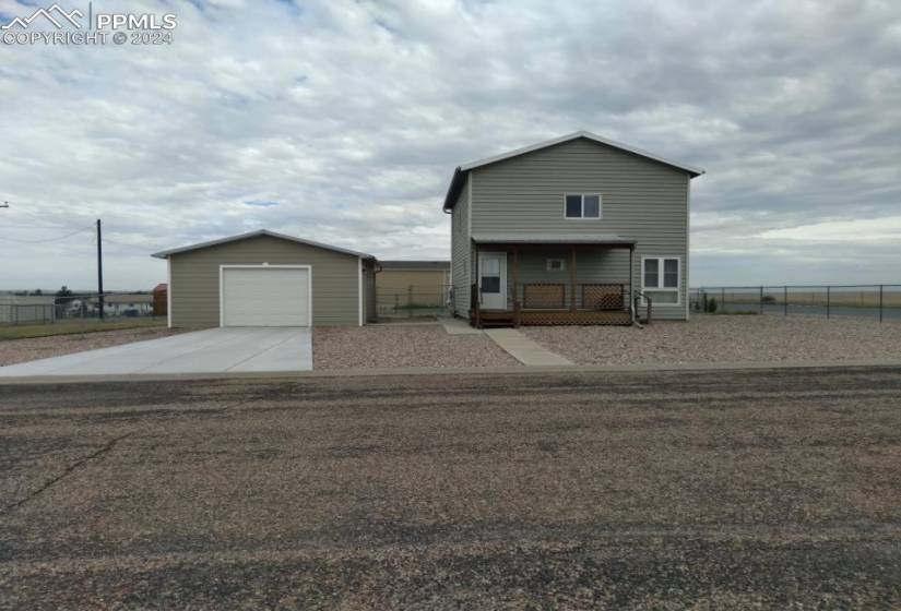 View of front facade with a garage, an outbuilding, and a porch