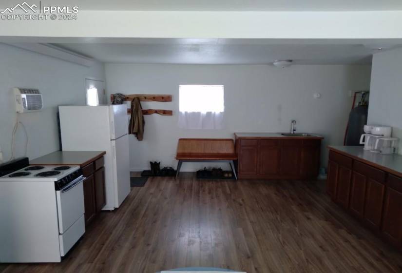 Kitchen with dark wood-type flooring, white appliances, sink, and a wall mounted AC