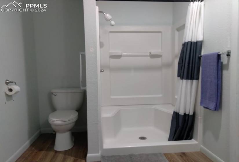 Bathroom featuring toilet, wood-type flooring, and walk in shower