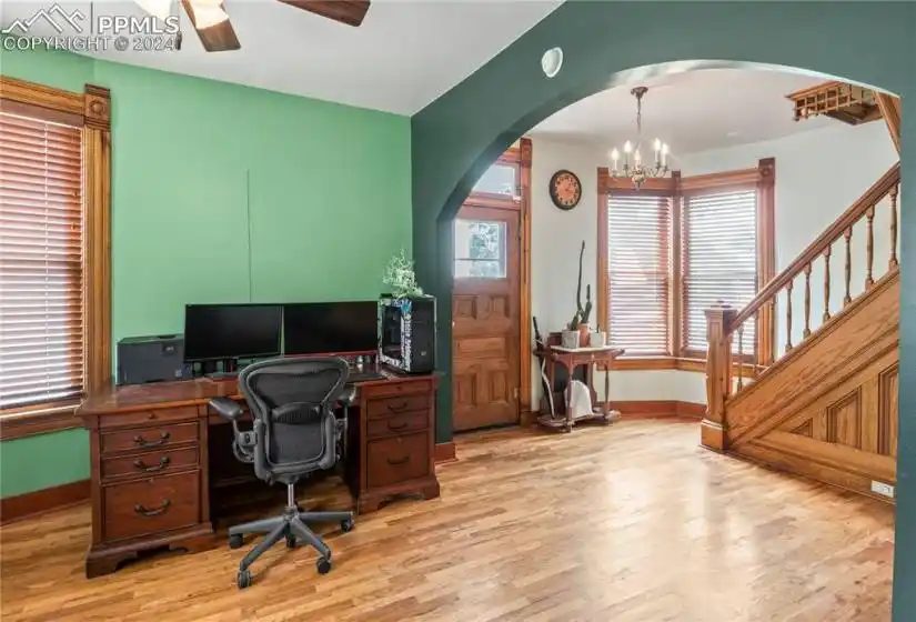 Entry parlor and living room with ceiling fan, chandelier and light hardwood flooring