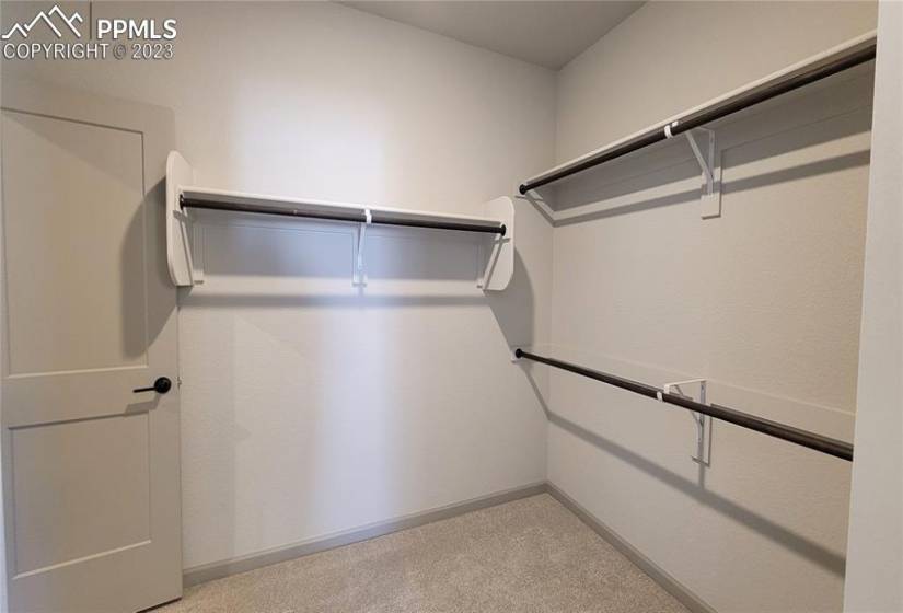 Primary Walk-In Closet with wood shelving and rods is conveniently attached to the laundry room!
